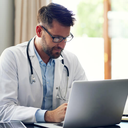 Doctor at desk using his laptop