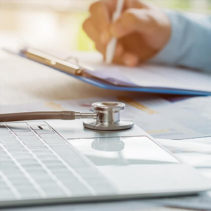 Doctor working in hospital writing prescription clipboard, working an Laptop on desk in hospital with report analysis