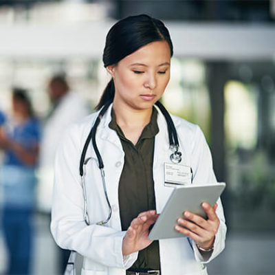 Young female physician scrolling on tablet device